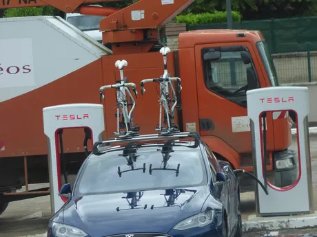 Tesla Model S mit zwei Rennrädern auf dem Dachträger an Tesla-Ladesäulen in Beaune (Frankreich)